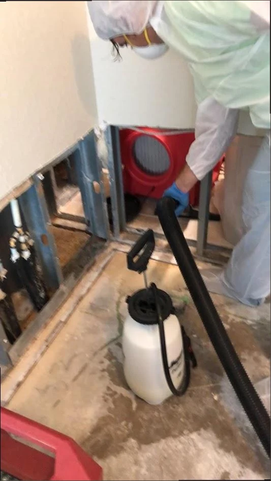 Technician in protective gear performing sewage cleanup and disinfection